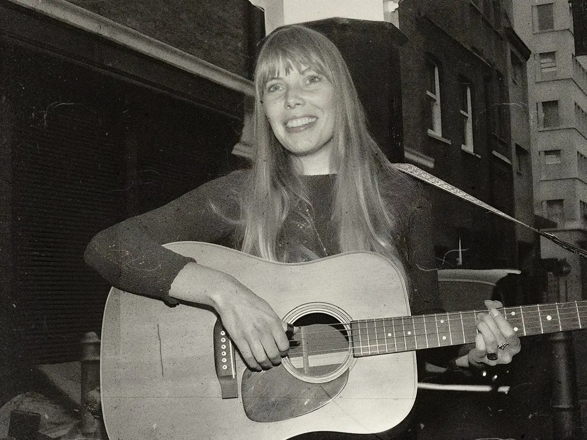 Joni Mitchell plays guitar outside The Revolution Club in London, 1968