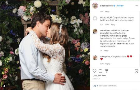   Bindi Irwin e Chandler Powell nel loro abito da sposa si baciano come rituale di matrimonio