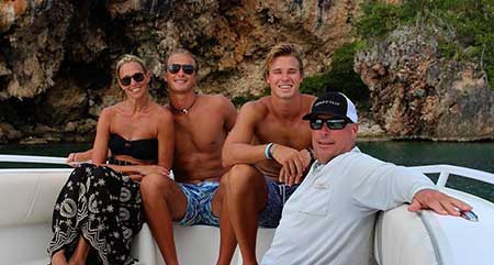 Christian Huff com seus pais e irmão sentados em um barco