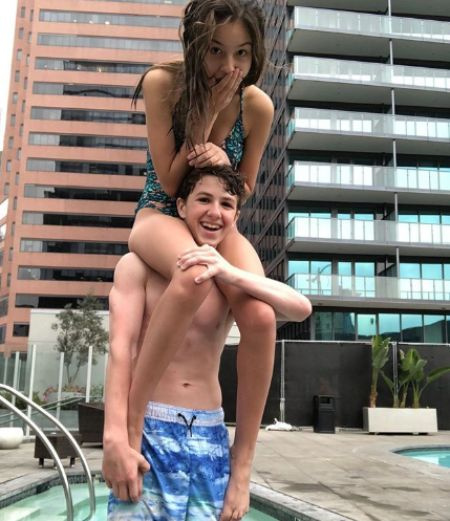   Olivia sentada sobre su novio Ethan's shoulder.
